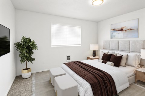a large bedroom with white walls, a window on back wall and carpet. Staged with a queen-sized bed, side tables, a plant and a flat screen TV.at North Pointe, Idaho, 83854