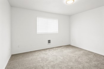 Bright empty bedroom with taupe carpet, white walls and white horizontal blinds on a window on the opposite wall. - Photo Gallery 23
