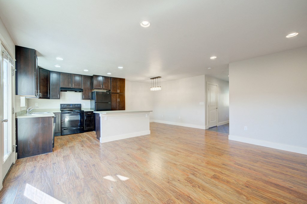 an empty living room and kitchen with wood flooring and black appliances at Copper Pines, Bozeman, MT