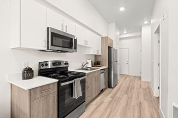 a kitchen with white cabinets and black appliances at The Duo, University Place, WA 98466