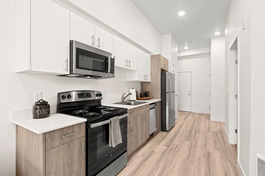 a kitchen with white cabinets and black appliances at The Duo, University Place, WA