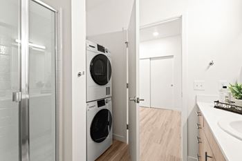 a white laundry room with a washer and dryer and a glass door at The Duo, University Place, WA