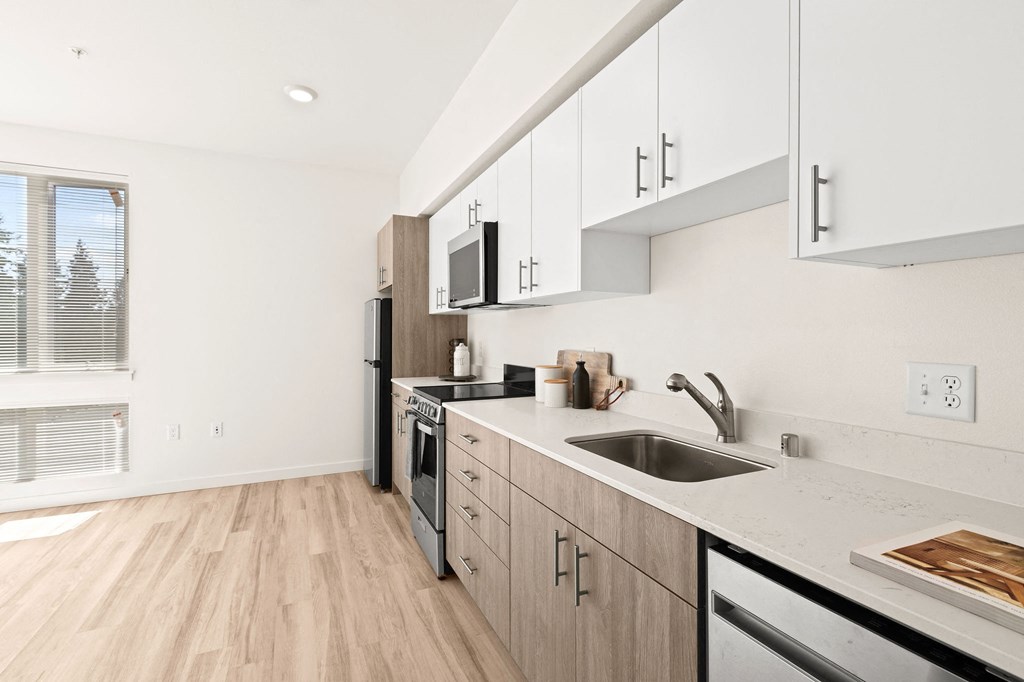 a renovated kitchen with white cabinets and a sink at The Duo, University Place, WA 98466