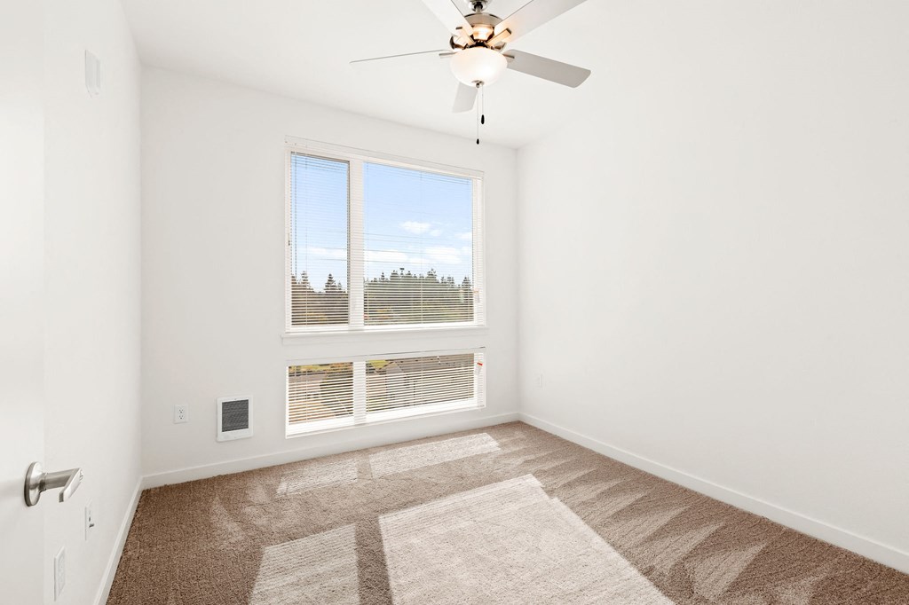 a bedroom with a large window and a ceiling fan at The Duo, University Place, WA