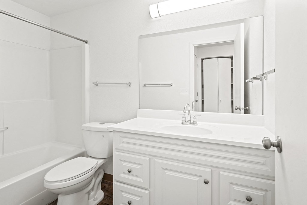 White bathroom with new white cabinets, large mirror, white toilet and full size bathtub.at North Pointe, Post Falls
