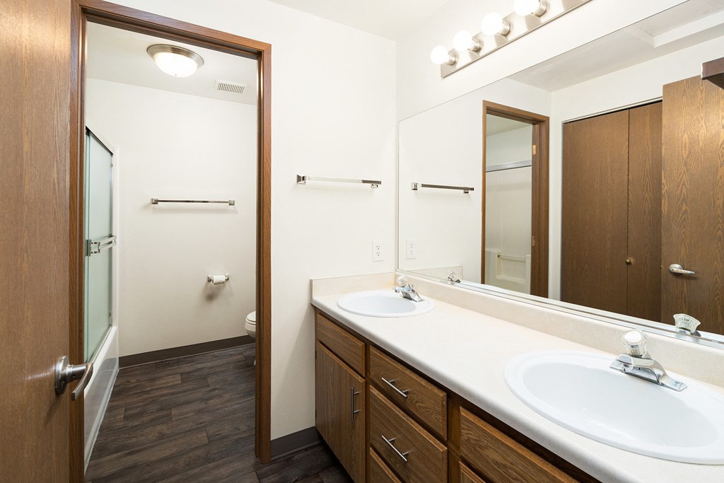A large full bathroom with double sinks, under cabinet storage, a linen closet directly across, and a doorway leading to the toilet and shower.at Clearwater, Post Falls, ID 83854