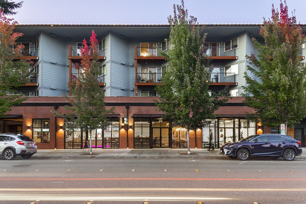 Building exterior at dusk with large green trees and balconies at 6 Wood Flats, Lacey Washington