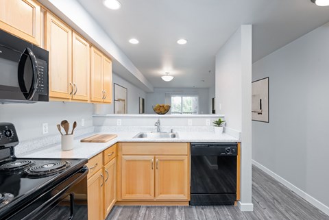A kitchen with black appliances and wooden cabinets.