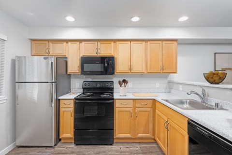 A kitchen with wooden cabinets and a black stove top oven at 6Wood Flats Apartments in Lacey, WA
