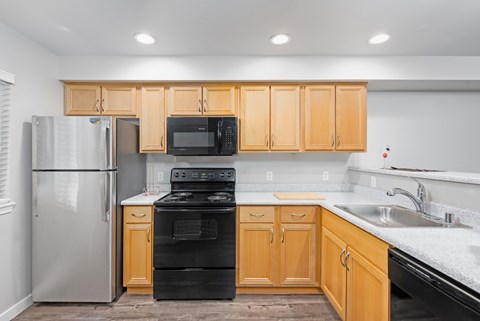 Modern kitchen with black appliances and wood cabinetry in a 663 square foot 1 bedroom apartment at 6Wood Flats Apartments in Lacey WA