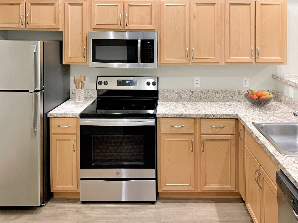 Corner style kitchen with wood cabinets and a stainless steel stove and microwave at 6 Wood Flats, Washington, 98503