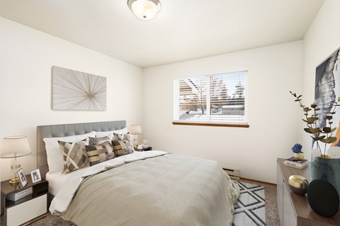 A bedroom with white walls, a large window on the back wall, and staged with a queen size bed, side tables, a dresser, and a rug.at Clearwater, Post Falls