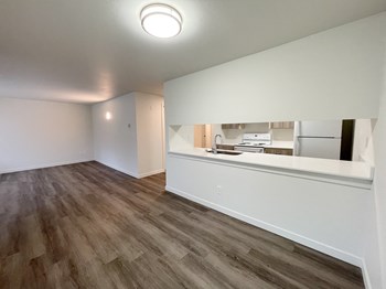 Open living room and dining area looks into the kitchen with white countertops. - Photo Gallery 3