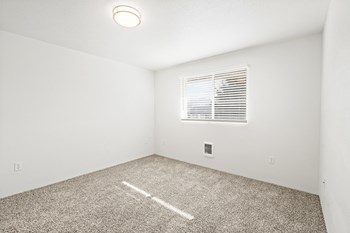 Bright empty bedroom with taupe carpet, white walls and white horizontal blinds on a window on the opposite wall. - Photo Gallery 26