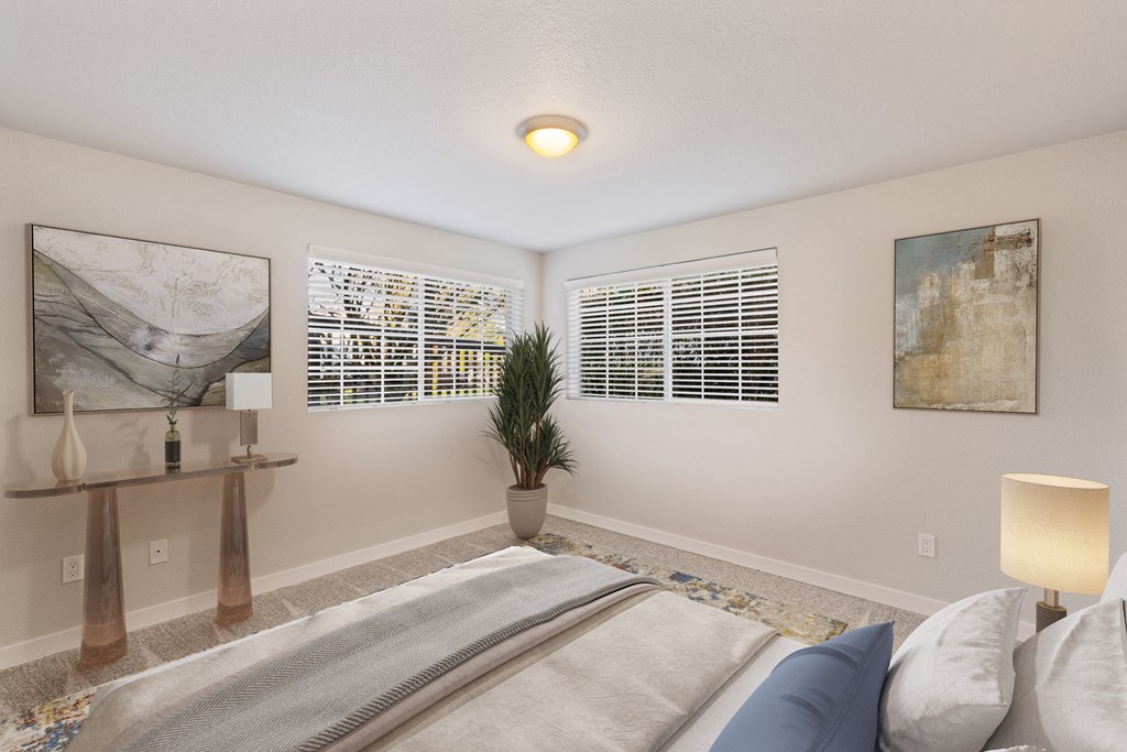 Bedroom with two large windows, staged bed, carpet, side tables and art on walls.at Capitol Crossing, Olympia
