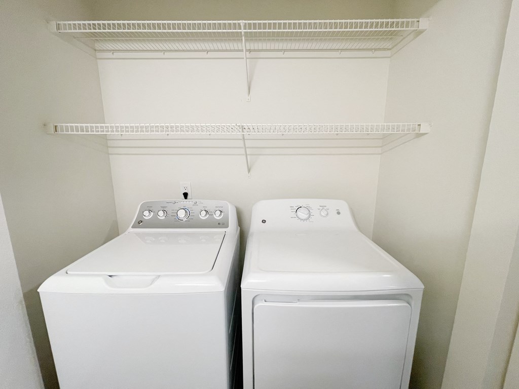 In-home top-loading washer and front-loading dryer with shelving storage above.at The Trail, Snohomish Washington