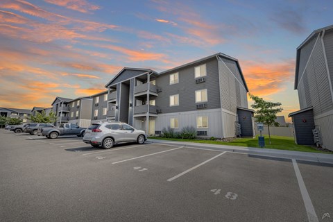 A parking lot with cars and apartment buildings in the background.