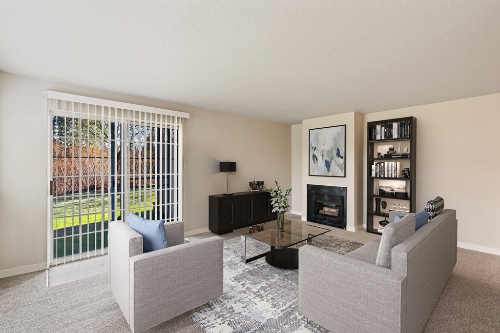 Carpeted living room, gas fireplace, and mantle in the center, with sliding glass doors to a grass lawn.at Capitol Crossing, Olympia, WA