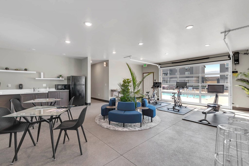Spacious clubhouse with overhead doors and a pool view. A workout area to the right, and a kitchen and seating on the left. at Altitude, East Wenatchee, Washington