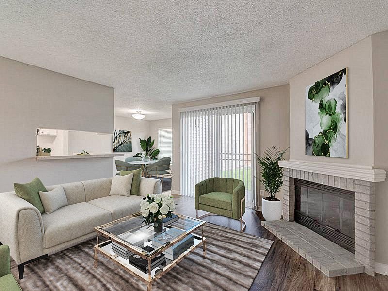 Living room with hardwood flooring, a large fireplace, and sliding glass doors to the private patio behind. Staged with a couch, chairs, and coffee table. at Pointe East, Fife, Washington