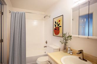 White bathroom with new white cabinets, large mirror, white toilet and full size bathtub.