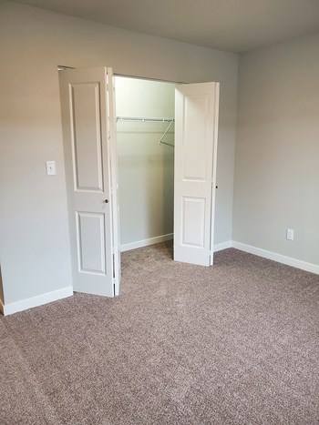 Bedroom closet with white bifold doors and shelf storage opens into the carpeted bedroom. - Photo Gallery 8