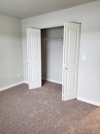 Large bedroom closet with double bi-fold doors, in-closet storage rack, carpeted, bright. - Photo Gallery 9