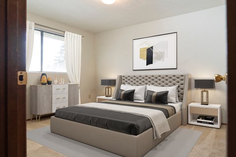 Large bedroom with natural light from window staged with bed, side tables, and wall art. at Hawks Prairie, Olympia