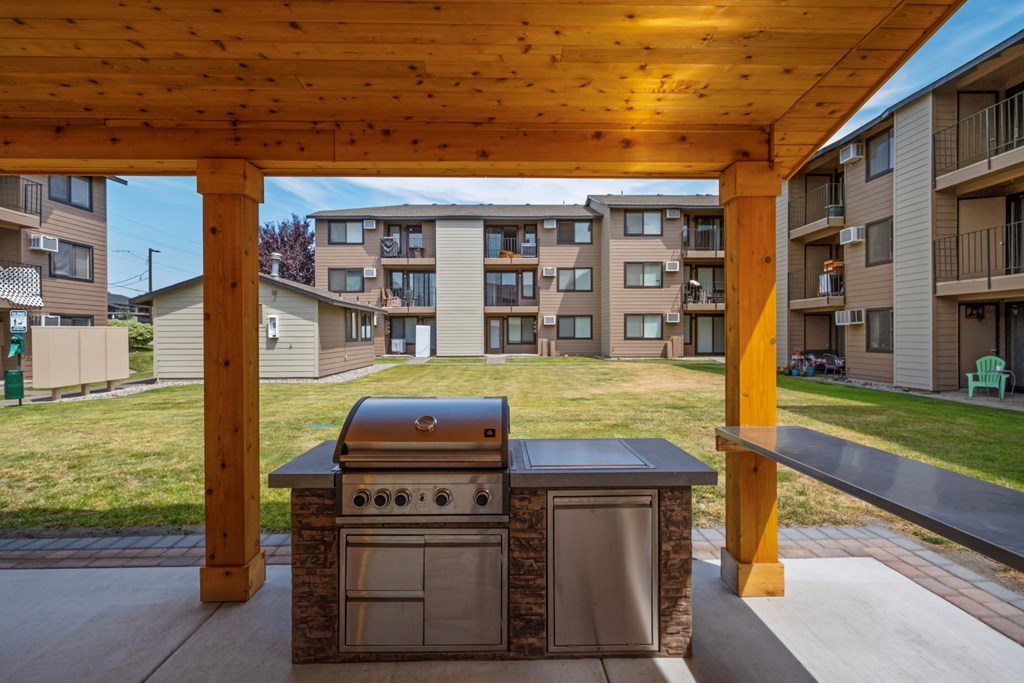a barbecue grill is under a wooden pavilion surrounded by green grass. at Brix, Walla Walla