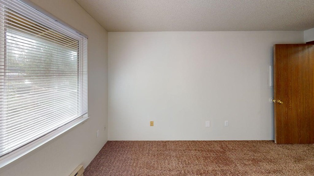 Second bedroom in a 2-bedroom unit at Heritage Grove Apartments Renton WA, with soft carpeting, large closet space, and a light-filled window.