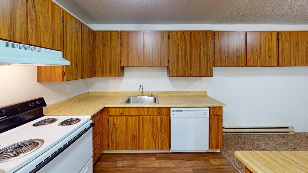 Well-equipped kitchen at Heritage Grove Apartments in Renton WA, with wood-grain cabinetry, full-size refrigerator, and modern finishes.