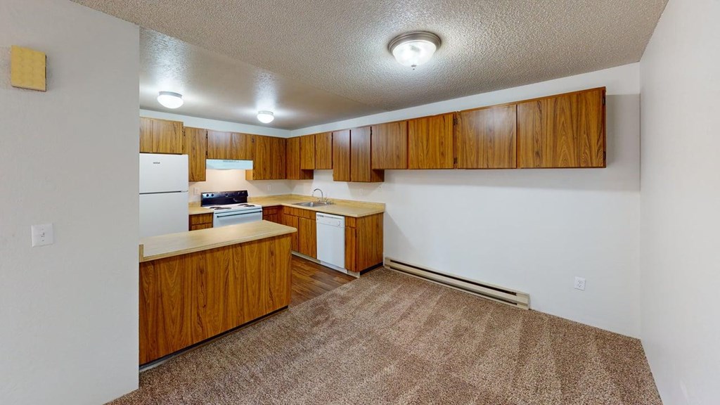 Spacious kitchen area at Heritage Grove Apartments Renton WA featuring timber-style cabinets, ample counter space, and overhead lighting.
