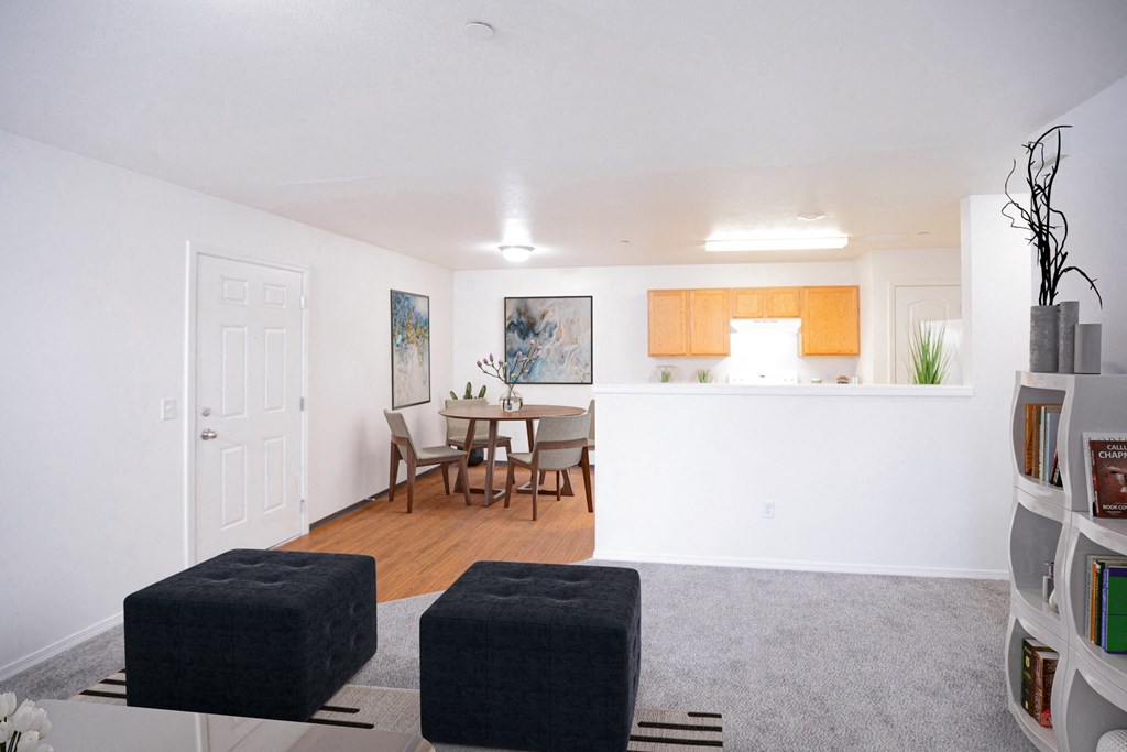 Big open living area with living room, dining area and kitchen with half wall visible. Taupe carpet in living room and faux wood flooring in dining and kitchen areas.at Canyon View, Idaho