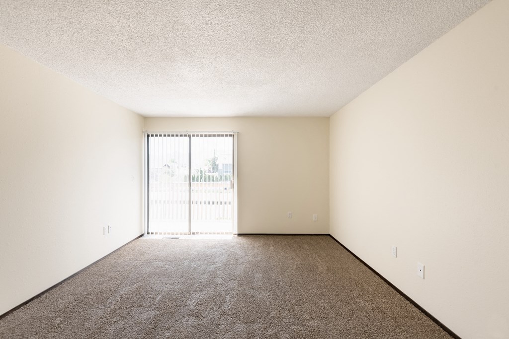 the spacious living room of an apartment with a large window