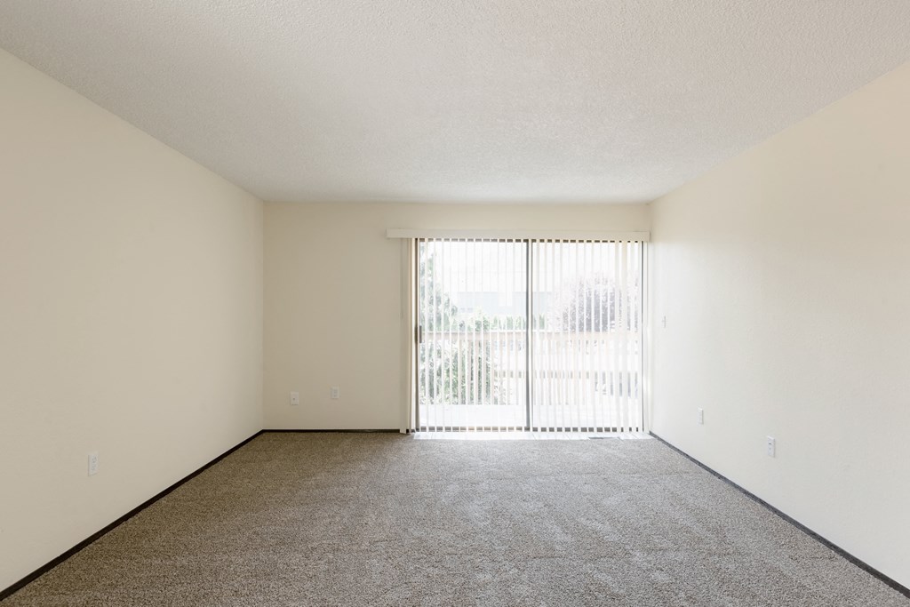 the spacious living room of an apartment with sliding glass doors