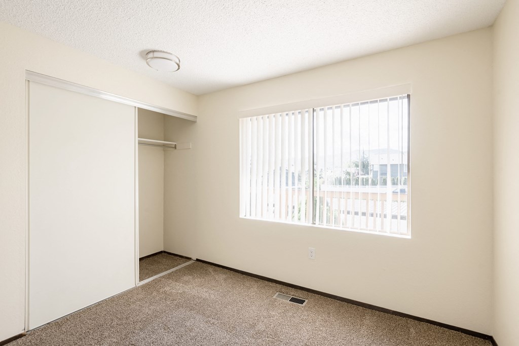 an empty living room with a large window and a closet