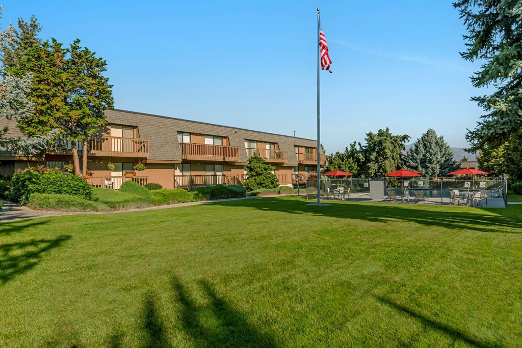 Grass courtyard with American Flag in center, swimming pool behind, and view of Beartooth Mountains.at Castlerock, Wenatchee, 98801