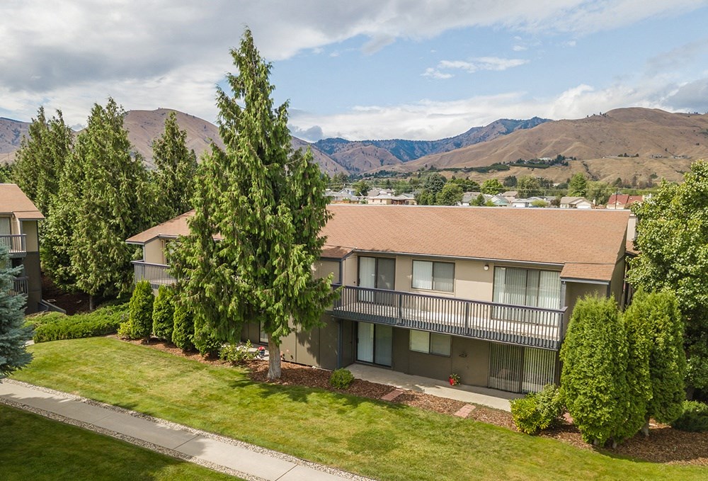 Outside apartments with oversized balconies, grass area & trees below, and view of the Wenatchee Mountains.at Cedarwood, Wenatchee, WA