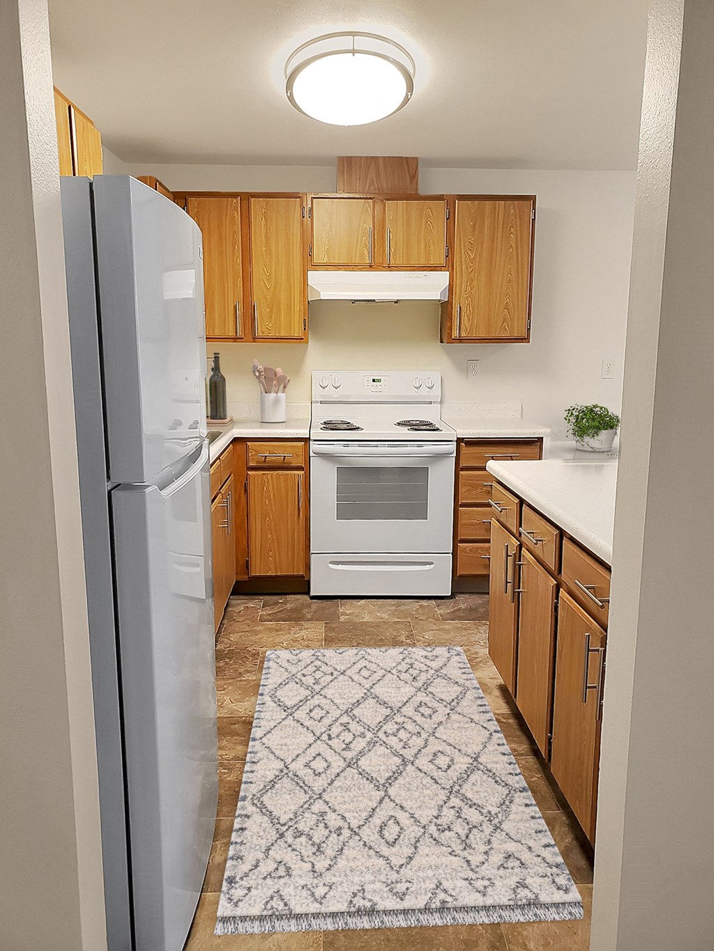 Kitchen with white counters, full-sized fridge, stovetop, oven, and range hood.at Clearwater, Post Falls Idaho