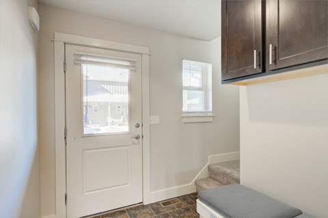 an entryway with a white door with a window and a staircase with a bench at Copper Pines, Montana