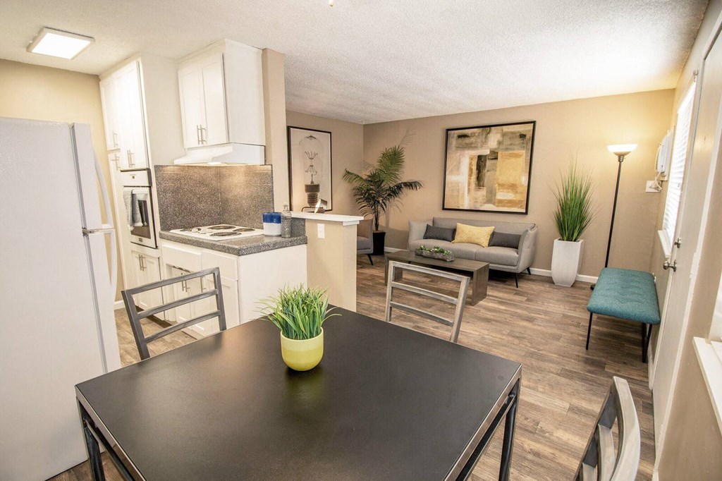 Dining area flows into kitchen and living room. Staged with dining set, couch, table, and plants