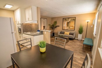 Woodland Village Living and Dining Dining area flows into kitchen and living room. Staged with dining set, couch, table, and plants. - Photo Gallery 4