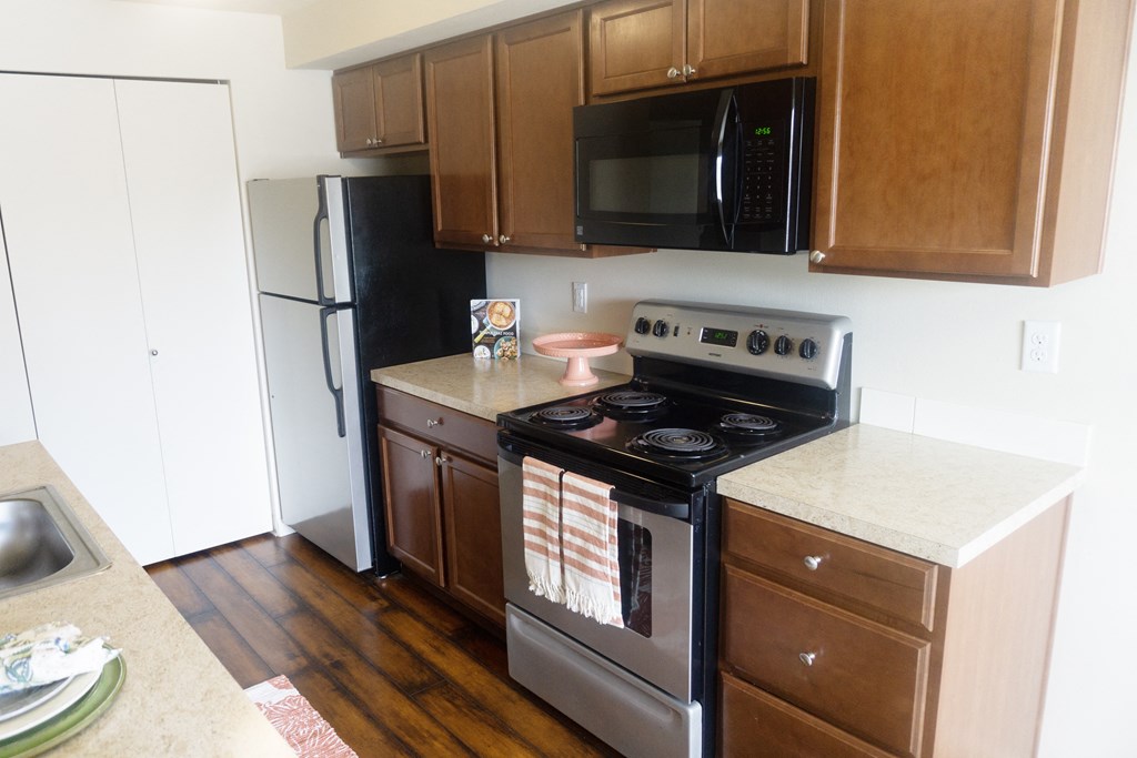 a kitchen with stainless steel appliances and brown wooden cabinets at Heritage Grove Apartments in Renton, WA