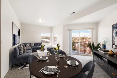 a dining area with a round table and chairs and a living room with a couch and wall art.