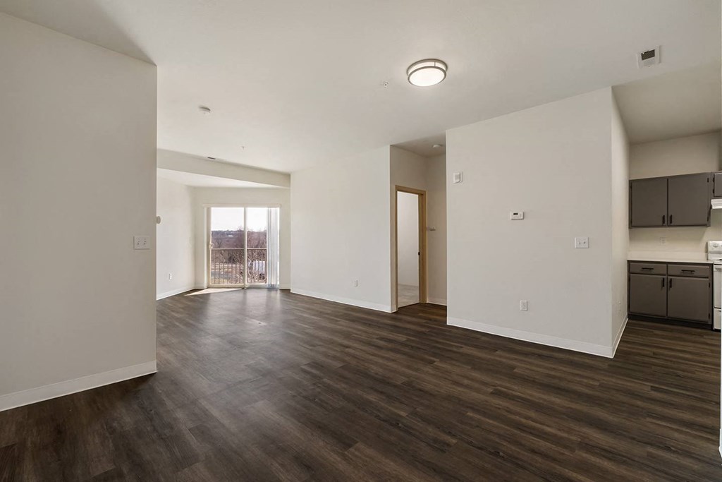 Large living area with wood flooring, bright white walls and sunny glass doors to balcony.at Shoreline Village, Richland Washington
