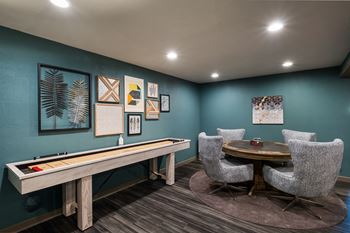 a game room with a shuffleboard table and chairs at Cedarwood, Renton Washington