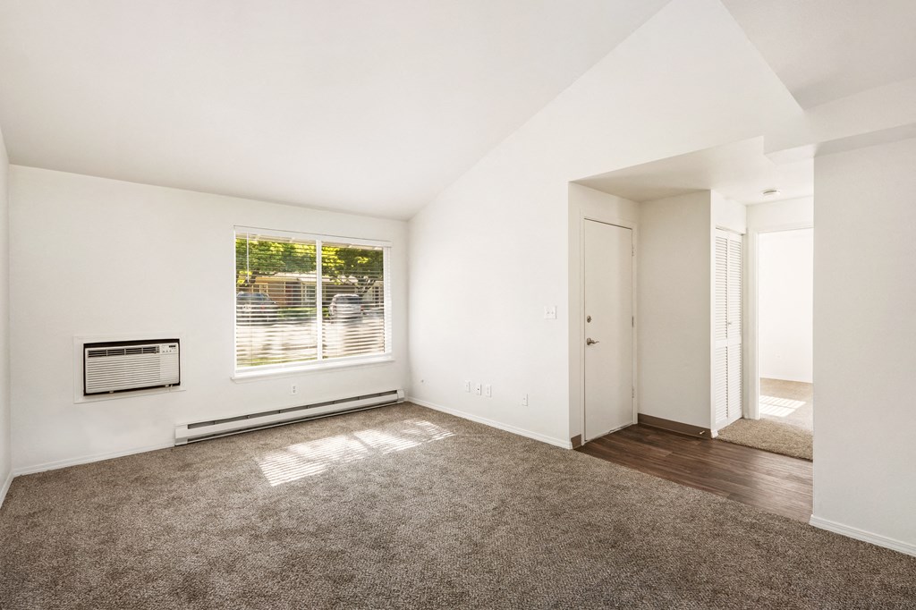 an empty living room with a large window and carpet at Park View Apartments, Wenatchee