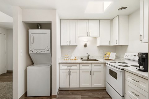 a kitchen with white cabinets and a white washer and dryer