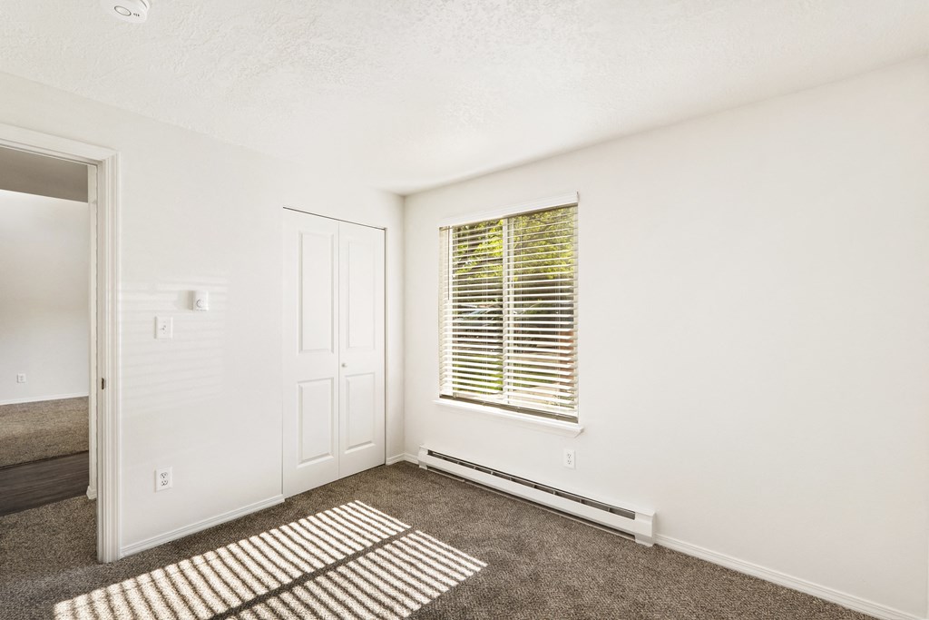 the living room of an apartment with carpet and a window  at Park View Apartments, Wenatchee, Washington