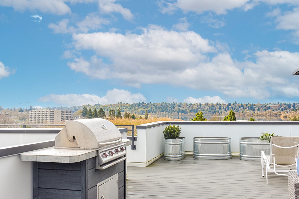 a roof deck with a barbecue grill and a view of the city